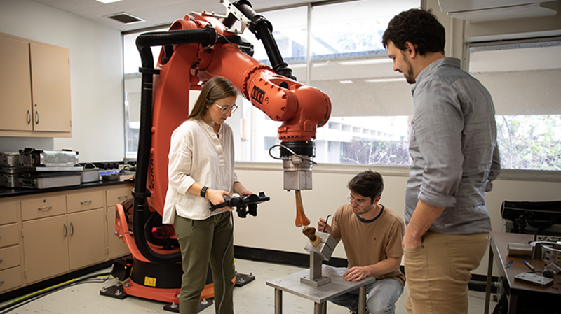 Left to Right: UCLA graduate students Ophelie Herve and Brandon Peterson, and assistant professor Tyler Clites work on simulating human movement of a knee joint using a large KUKA robot. UCLA Samueli.