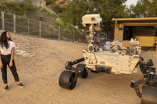 Zarifian stands with Perseverance’s twin testbed, OPTIMISM, in the Mars Yard at JPL.